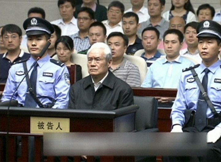 Zhou Yongkang, China's former domestic security chief, sits between his police escorts as he listens to his sentence in a court in Tianjin, China.