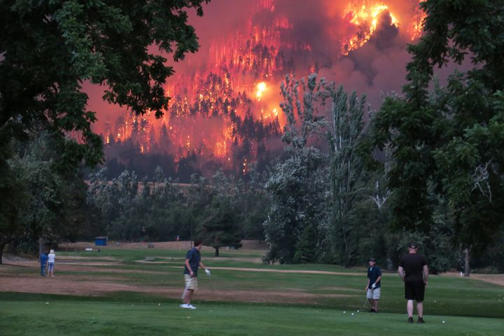 Golfers play in North Bonneville, Washington, last fall as the Eagle Creek wildfire burns. The U.N.'s Intergovernmental Panel on Climate Change said the world must drastically cut greenhouse gas emissions to avoid climate disaster.