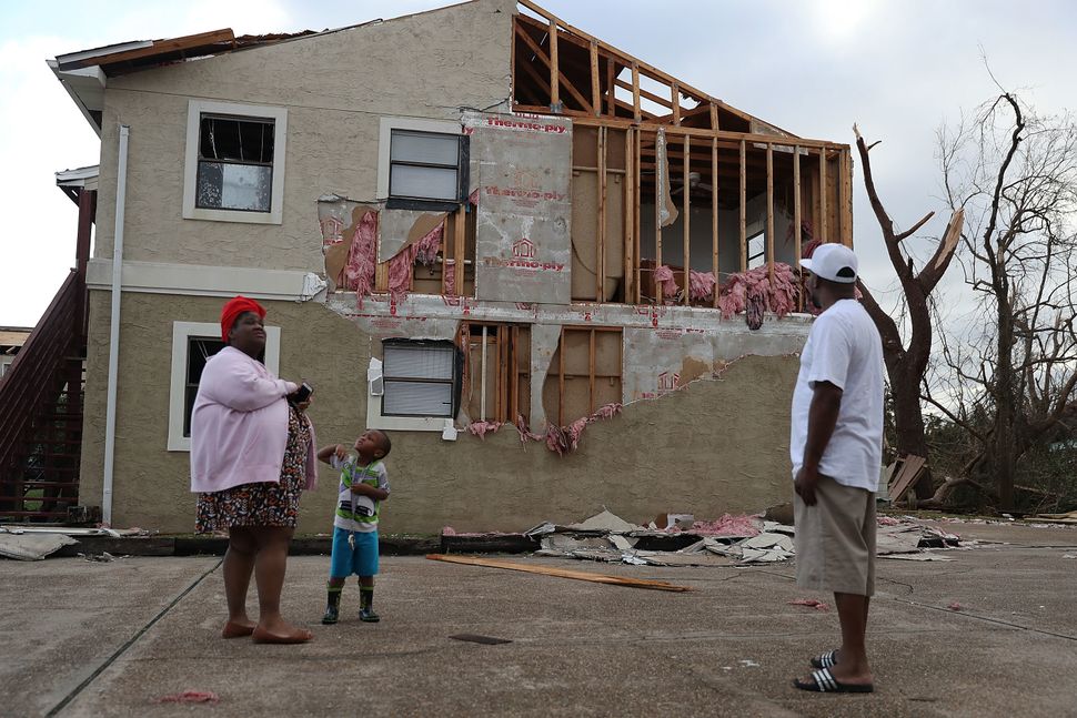 Comeasha Stanley, Ramari Stanley and Terrell Atkinson stand near a heavily damaged apartment in Panama City.&nbsp;