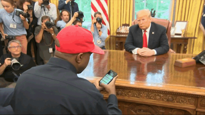 A short video clip of Kanye West entering his passcode on his smartphone across a table from Donald Trump.