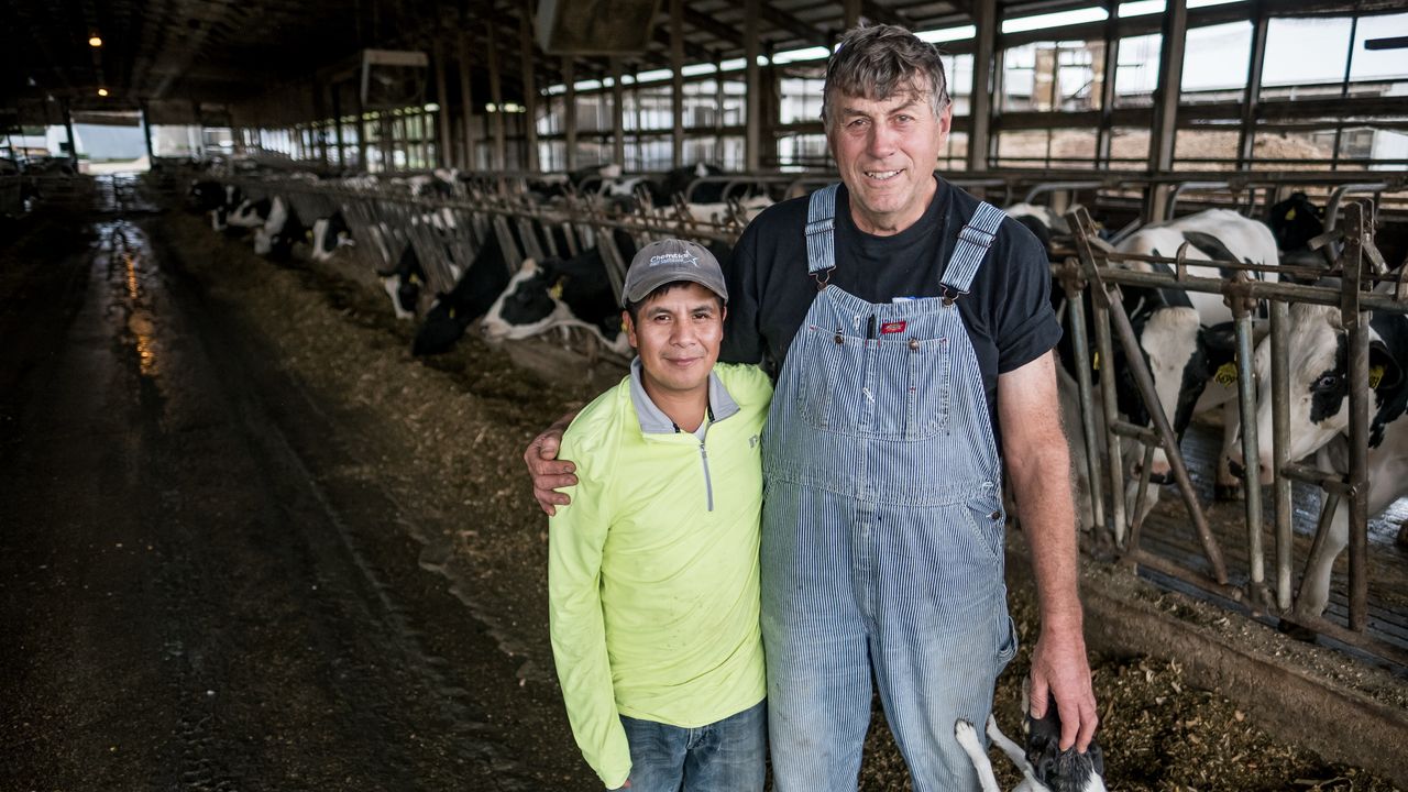 Roberto Tecpile (left), a farm worker from Veracruz, Mexico, and John Rosenow (right), owner of Rosenholm dairy farm, pose for a portrait at the farm in Cochrane, Wisconsin, in October.