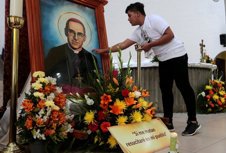 A Catholic man touches a photo of the late archbishop of San Salvador, Oscar Arnulfo Romero, at a Mass at the Metropolita