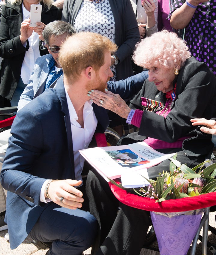 Prince Harry greets royal fan and war widow Daphne Dunne as they arrive for a public walkabout at the Sydney Opera House on Oct. 16, in Sydney, Australia. 