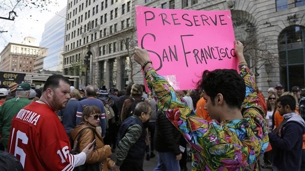 Shane Zaldivar holds up a sign as crowds jam a Super Bowl event in San Francisco. Zaldivar said the sign was a protest against the lack of affordable housing in the city. There’s been a spate of legislation at the state and federal level this year addressing zoning for affordable housing.