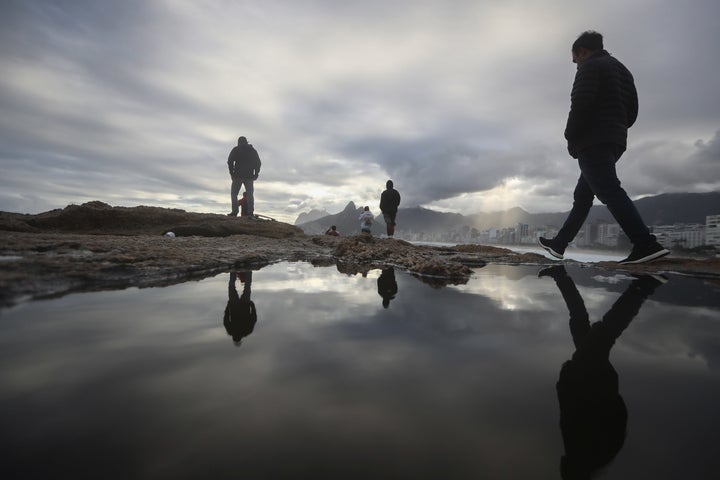 People walk along Arpoador Beach during strong winter swells on the Atlantic Ocean in August 2017 in Rio de Janeiro. Scientists say that sea level rises caused by climate change would make Rio among the Earth's most imperiled cities.