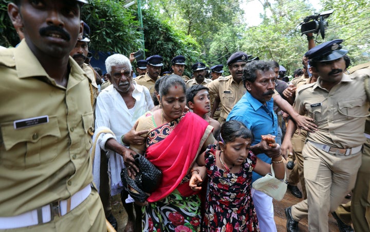 Police escort a woman and her family after she was harassed by protesters while seeking the entry to the Lord Ayyappa Temple in Sabarimala on Oct. 17, 2018.