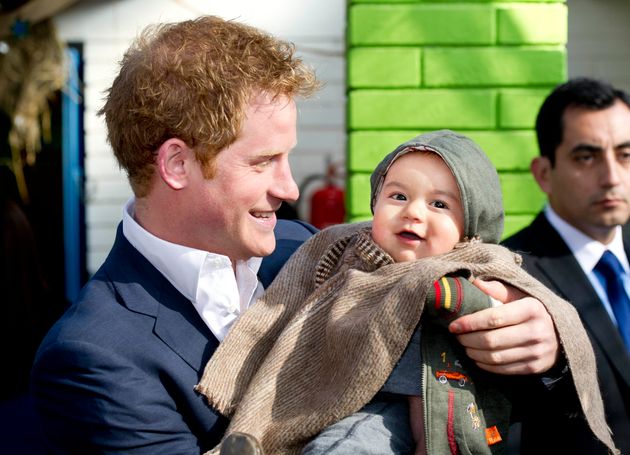 Prince Harry holds young Matias Gonzalez as he visits a the Sagrada Familia kindergarten, a kindergarden of indigenous children on June 27, 2014 in Santiago, Chile. 