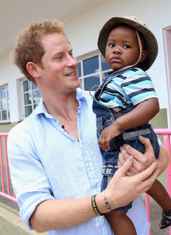 Prince Harry holds a young child during a visit to Thuso Centre for children living with multiple disabilities on December 7, 2014 in Bute-Bute, Lesotho.