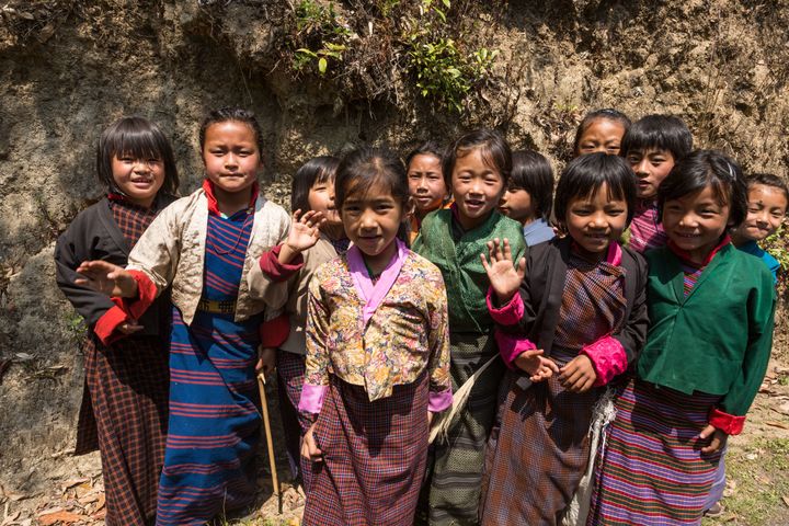 Young schoolgirls in traditional dress pose for their picture by the road in Talo, Bhutan.