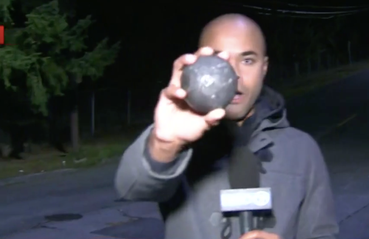 KIRO TV journalist Michael Spears shows one of the two-pound metal balls that fell out of a truck in Seattle on Thursday.