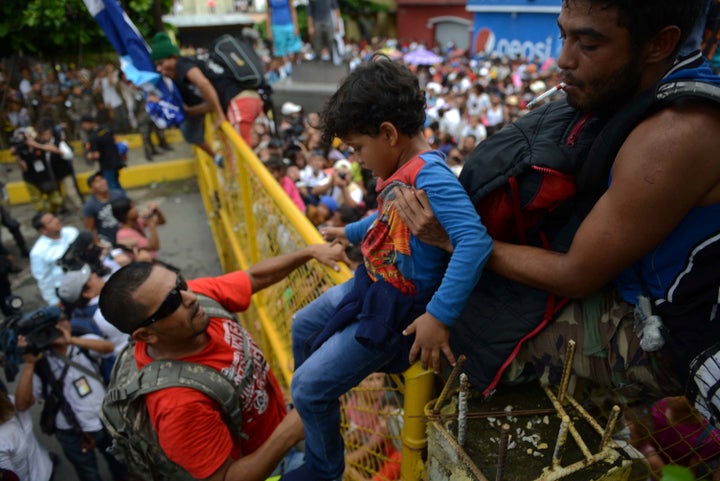 A child is passed over a border fence between Guatemala and Mexico on Friday.