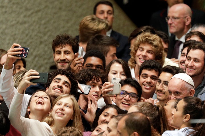 Pope Francis, right, poses with youths attending the Synod at the end of his meeting in the Paul VI hall at the Vatican, Saturday, Oct. 6, 2018.