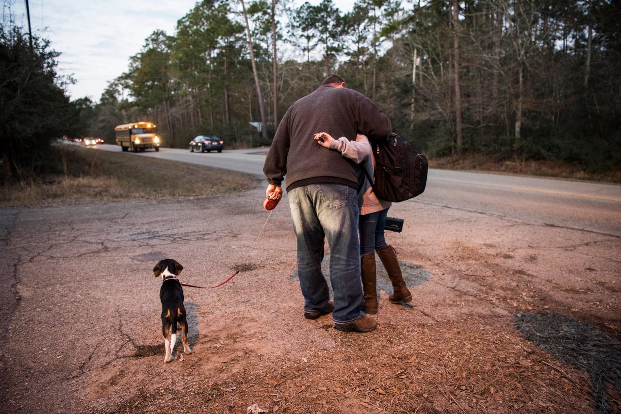Tom walks his middle daughter, Jenna, to the school bus stop along with the family's new puppy. A few weeks after this photo was taken, they gave the dog away to Glenda because they weren't able to keep up with her care.
