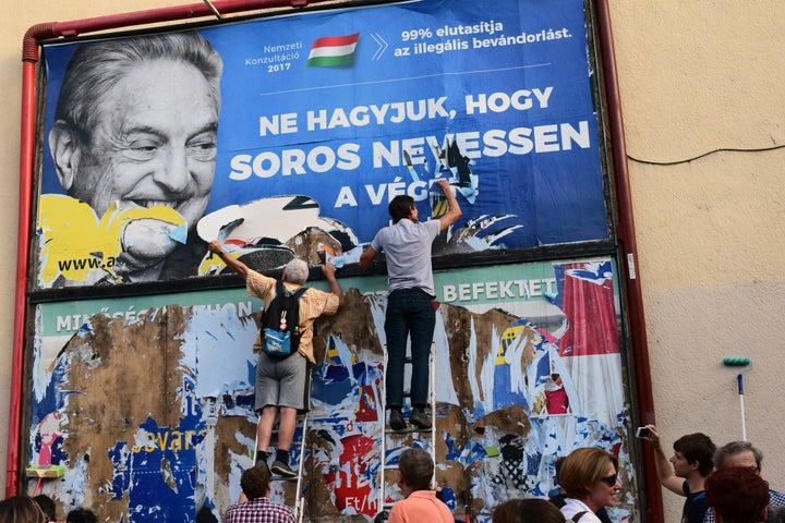 In this July 2017 photo, activists of the Egyutt (Together) party tear down an ad by the Hungarian government against Soros in Budapest.