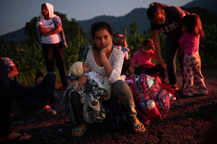 A migrant woman rests roadside with her child while traveling with a caravan of thousands from Central America en route to th