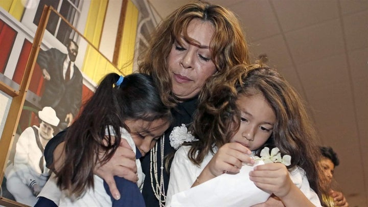 <p>A woman comforts two children under her legal guardianship in Miami last year. One in five children being raised by extended family members live in an immigrant household, a new report shows. </p>