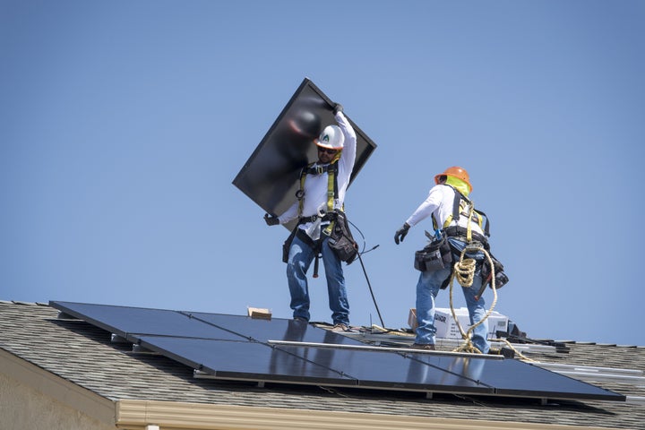 Workers install solar panels on a rooftop in California.