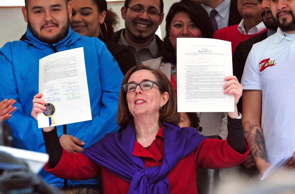 Gov. Kate Brown holds up an immigration bill in May. She's been actively fighting President Donald Trump's anti-immigrant pol