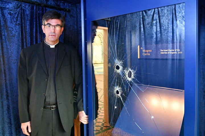 The Very Rev. Nick Papadopoulos stands next to the damaged glass case.