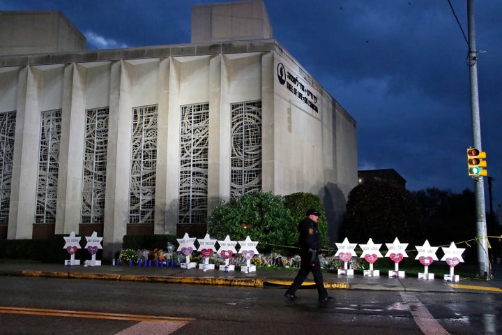 Un oficial de policía pasa junto a la Sinagoga del Árbol de la Vida y un memorial de flores y estrellas en Pittsburgh el domingo 28 de octubre