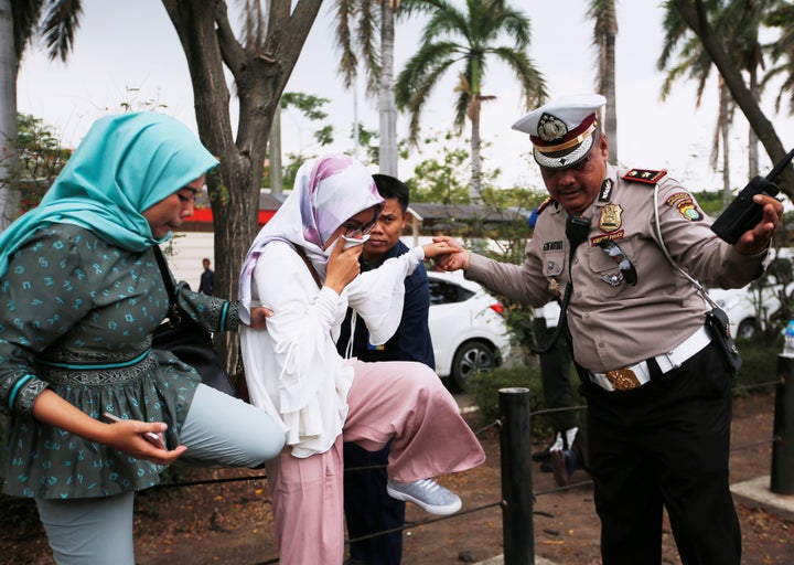 A woman is helped by a policeman as she arrives at a crisis center at Soekarno Hatta International airport near Jakarta