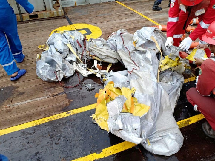 Workers examine recovered debris from what is believed to be flight JT610.