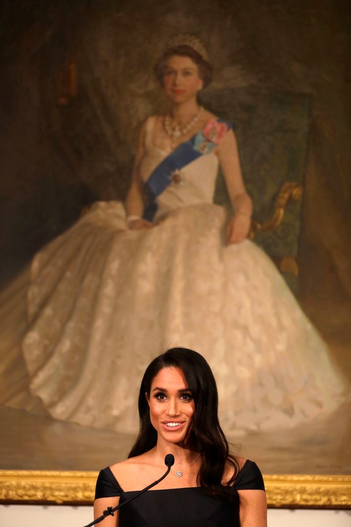 The Duchess of Sussex delivers the speech in front of a portrait of Queen Elizabeth II. 
