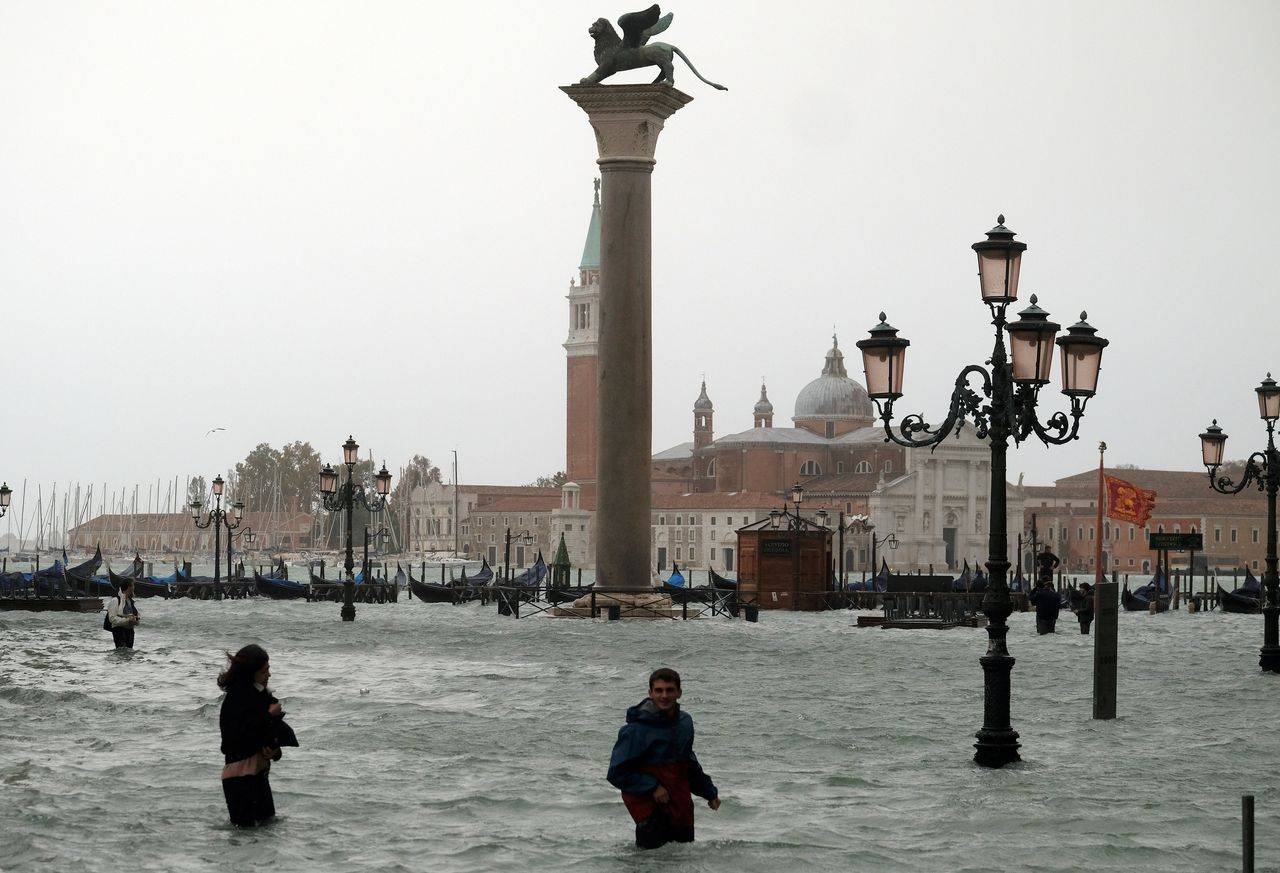 People walk in flooded Piazza San Marco during a period of seasonal high water in Venice, Italy.