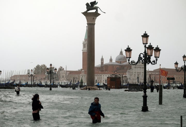 People walk in flooded Piazza San Marco during a period of high seasonal waters in Venice, Italy.