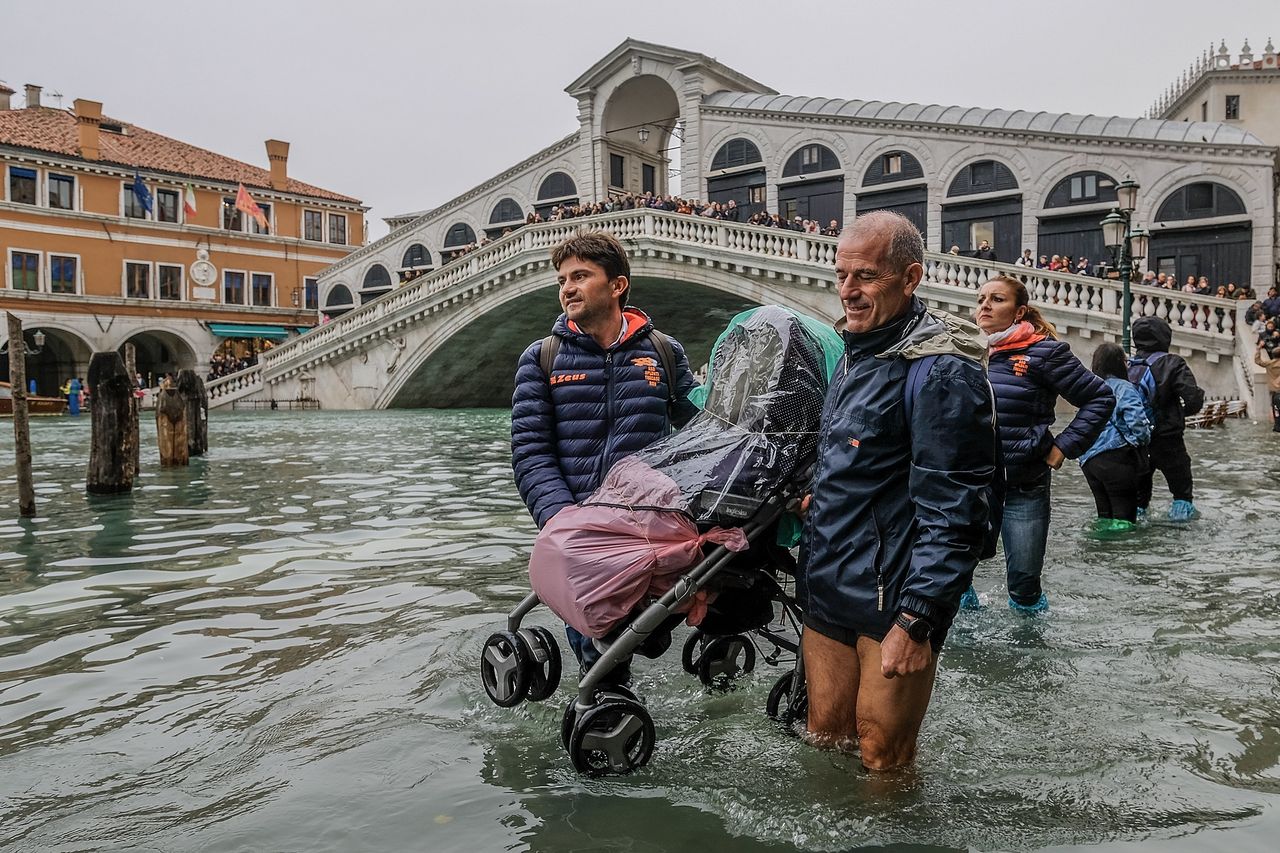 Tourists carry a stroller through the flood waters.