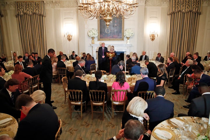 President Donald Trump bows his head as pastor Paula White leads the room in prayer during a dinner for evangelical leaders in the State Dining Room of the White House on Aug. 27, 2018.