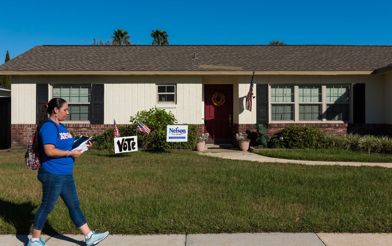 Arleen Sevilla walks by a house with signs supporting Sen. Bill Nelson (D-Fla.) while canvassing in Orlando.