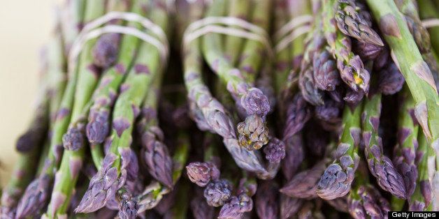 Close up of fresh, vibrant asparagus with purple tips at farmers market.