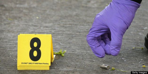 CHICAGO, IL - MAY 14: A Chicago Police investigator picks up a shell casing left in the street at the scene of a shooting in the South Shore neighborhood on May 14, 2013 in Chicago, Illinois. The shooting was the first of several that left two men dead and 11 others wounded in the city between Monday afternoon and the early hours of Tuesday morning. (Photo by Scott Olson/Getty Images)