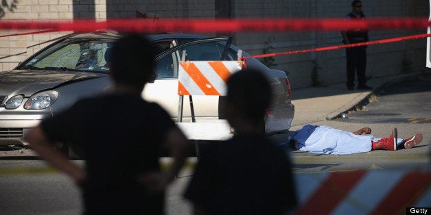 CHICAGO, IL - JULY 11: Young boys watch as Chicago police invesitgate a shooting death on July 11, 2013 in Chicago, Illinois. A 27-year-old man died on the scene after being shot in the chest. Chicago has had more than 200 homicides so far in 2013 and has had more than 1000 people shot. There have been more than 21 murders in July. (Photo by Scott Olson/Getty Images)