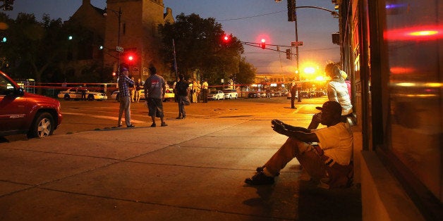 CHICAGO, IL - AUGUST 19: Neighborhood residents watch as Chicago police investigate a shooting in front of the Uptown Baptist Church on August 19, 2013 in Chicago, Illinois. Five people were shot, one fatally, during the drive-by shooting in which gunmen fired more than 20 rounds at a group of people standing in front of the church. At least 9 people have been killed and about 30 others wounded in shootings in the city over the past 4 days. (Photo by Scott Olson/Getty Images)