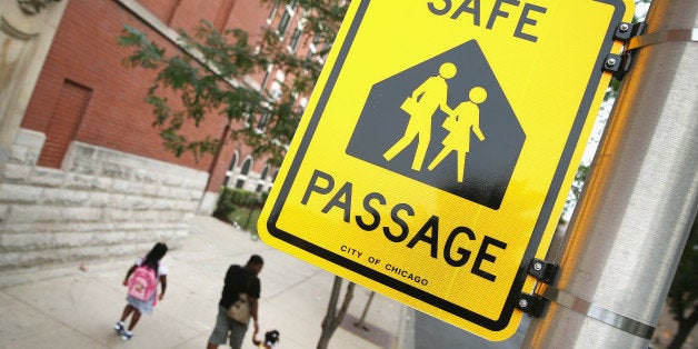 CHICAGO, IL - AUGUST 28: Students walk along a designated Safe Passage route to Laura Ward Elementary School on the Westside on August 28, 2013 in Chicago, Illinois. The Safe Passage program was started because parents were worried about their childrens safety while they walked to school across gang boundaries after the city closed 49 elementary schools and moved the students to nearby schools. Police, city workers and Chicago Public Schools personnel are posted along the route to provide 'safe passage' for the students. (Photo by Scott Olson/Getty Images)