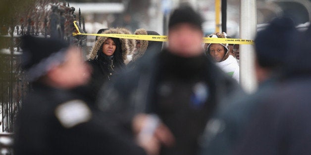 CHICAGO, IL - DECEMBER 15: Neighborhood residents watch as police investigate a homicide scene after a 24-year-old man was f