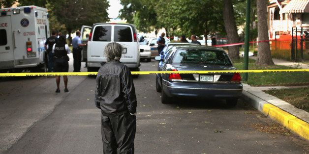 CHICAGO, IL - SEPTEMBER 20: A woman watches as police investigate the shooting death of 14-year-old Tommy McNeal on September 20, 2013 in Chicago, Illinois. McNeal was one of at least 3 killed and about 30 wounded by gunfire in the city in the past 24 hours. (Photo by Scott Olson/Getty Images)