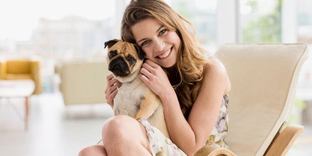 Smiling woman holding cute, small dog on lap