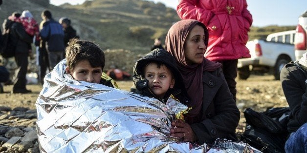 A Syrian family waits after arriving on the Greek island of Lesbos along with other migrants and refugees, on November 17, 20
