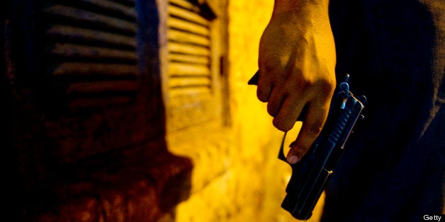 ASSIUT, EGYPT - JUNE 24: A young man in an alley holds a Beretta 9mm unliscenced pistol purchased illegally on June 24, 2013