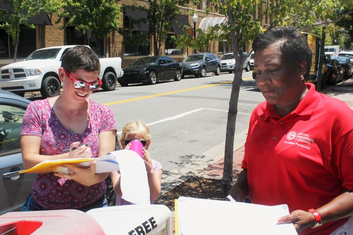 Rachelle Tracy signs a petition in downtown Little Rock, Arkansas, from canvasser Cynthia Ford in favor of putting a minimum wage hike proposal on the ballot. It passed Tuesday.
