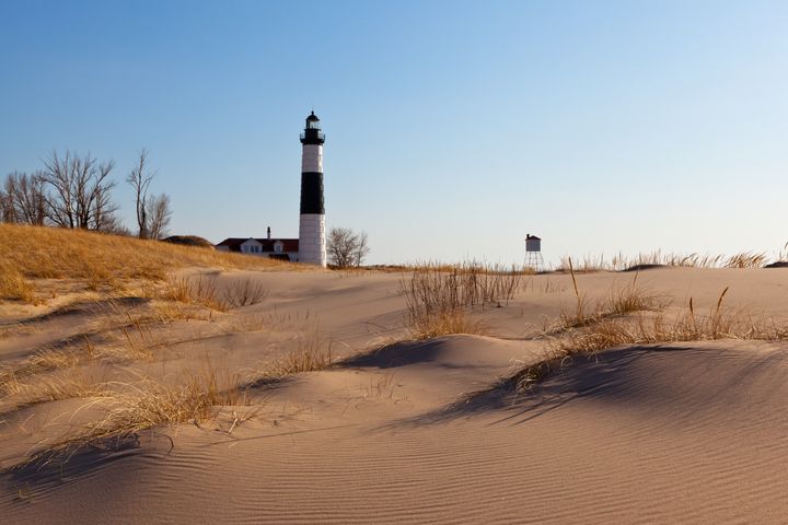 Windswept sand dunes displaying their ripples in front of Big Sable Point Lighthouse on shores of Lake Michigan.