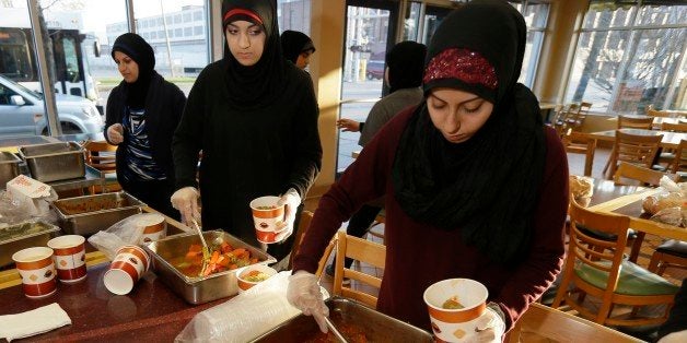 Volunteers Zahraa Debaja, center, and Zeinab Makki, right, prepare meals from food provided by the Yasmeen Bakery in Dearborn, Mich., Friday, April 25, 2014. The reach of one of the nationâs few charitable organizations exclusively providing halal food to the poor could be greatly expanded under the new federal provision. Zaman International Inc. is based in Dearborn, which has a large Muslim population has provided about 250 tons of hot and dry food since 2010 and serves about 150 families with a monthly food box and vouchers. (AP Photo/Carlos Osorio)