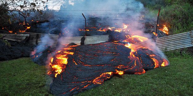 This Tuesday, Oct. 28, 2014 photo provided by the U.S. Geological Survey shows lava that has pushed through a fence marking a property boundary above the town of Pahoa on the Big Island of Hawaii. After weeks of slow, stop-and-go movement, a river of asphalt-black lava was less than the length of a football field from homes in the Big Island community Tuesday. The lava flow easily burned down an empty shed at about 7:30 a.m., several hours after entering a residential property in Pahoa Village, said Hawaii County Civil Defense Director Darryl Oliveira. A branch of the molten stream was less than 100 yards (90 meters) from a two-story house. It could hit the home later Tuesday if it continues on its current path, Oliveira estimated. Residents of Pahoa Village, the commercial center of the island's rural Puna district south of Hilo, have had weeks to prepare for what's been described as a slow-motion disaster. Most have either already left or are prepared to go. (AP Photo/U.S. Geological Survey)