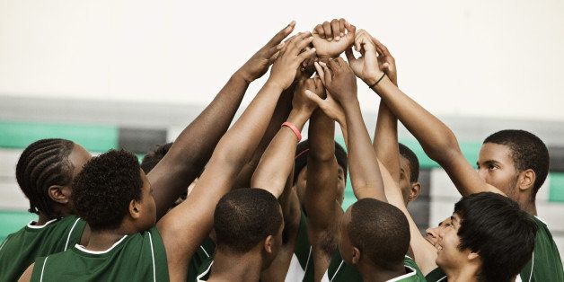 Basketball team with arms raised in huddle