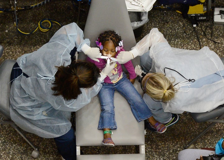 LOS ANGELES, CA - SEPTEMBER 27: Kamora Cyprian, 2, gets her teeth cleaned as part of a free health care service at the Care Harbor clinic at the Los Angeles Sports Arena on September 27, 2012 in Los Angeles, California. Care Harbor is expected to give free medical, dental and vision care to 4,800 uninsured patients at the event, which runs from September 27-30. In Los Angeles County it is reported that 2.2 million people do not have health insurance, which includes an estimated 227,000 young and school-aged children. (Photo by Kevork Djansezian/Getty Images)