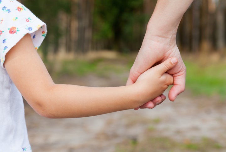 Mother holding a hand of her daughter in spring day outdoors