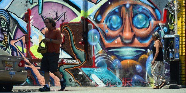 Pedestrians walk past vividly colorful murals on a building's exterior in the Arts Distrct near downtown Los Angeles on August 16, 2013 in California. AFP PHOTO/Frederic J. BROWN (Photo credit should read FREDERIC J. BROWN/AFP/Getty Images)